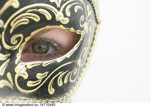 A woman behind a Venetian Carnival mask with her eye peeking through  Nashville  Tennessee.