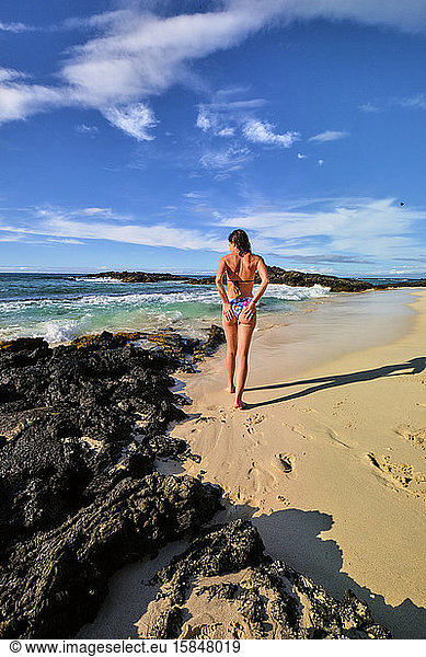 A woman brushes the sand from her bikini as she walks along Makalawena