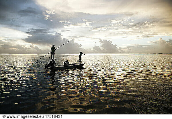 A woman casts her fly line from a boat in the florida keys at sunset