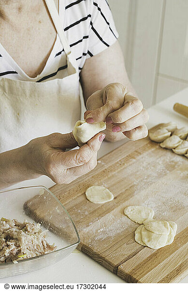A woman cooks Russian dumplings  hands close-up  step-by-step recipe.