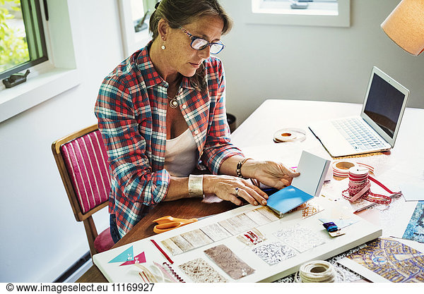 A woman creating a collage picture with material and paper.