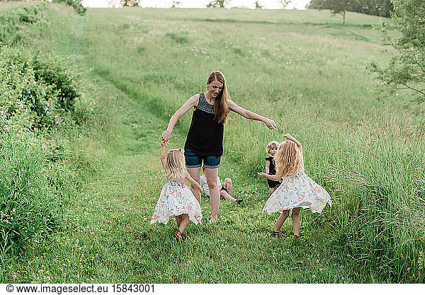 A woman dancing with kids in a meadow.