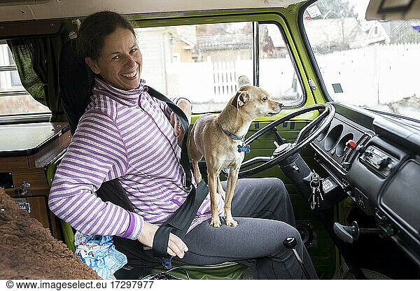 A woman driver with dog on her lap in VW camper van