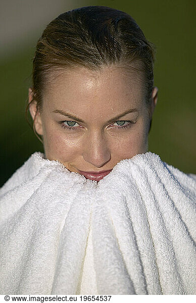A woman drying her face with a towel.