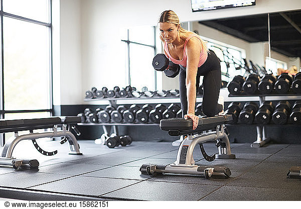 A woman exercising with weights in a gym.