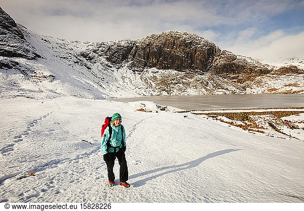 A woman hill walker by a frozen Stickle Tarn in the Langdales  Lake District  UK