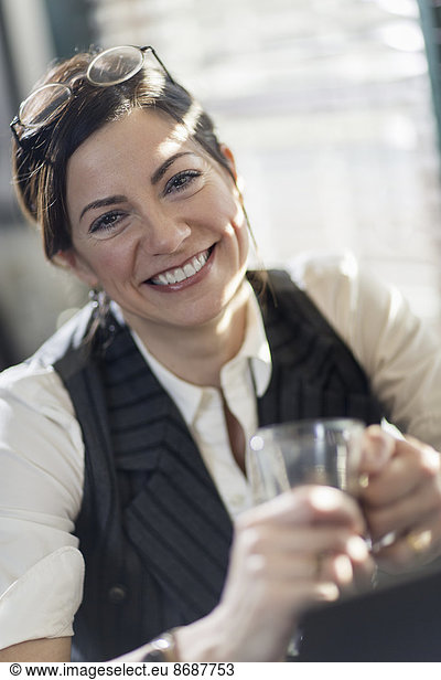 A woman holding a glass and smiling at the camera. A working lunch.