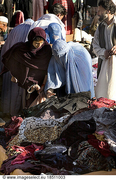 A woman in a headscarf shops side by side with women in burqas at a market in Kabul  Afghanistan.
