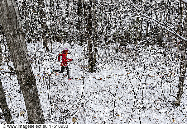 A woman in a red Jacket running in winter.