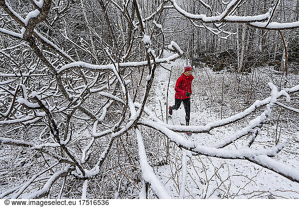 A woman in a red Jacket trail running in winter.