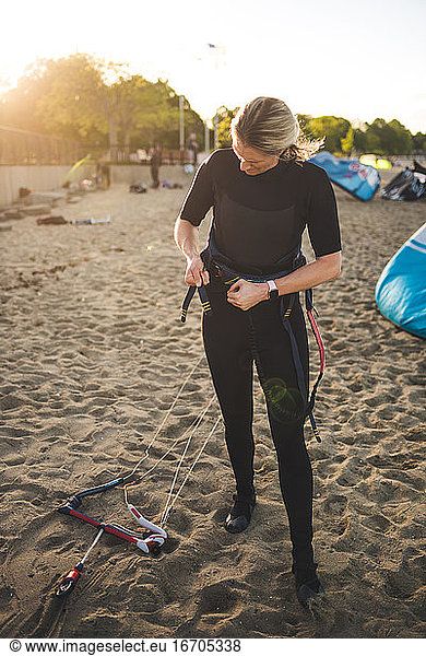 A woman in a wetsuit prepares to go kiteboarding in Boston