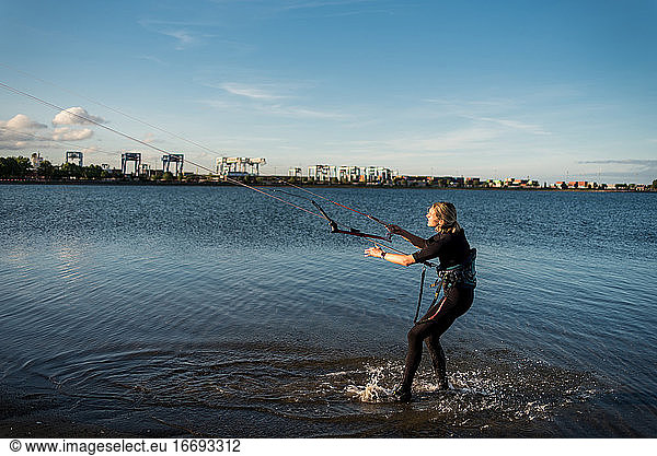 A woman in a wetsuit rigs up her kite before kiteboarding
