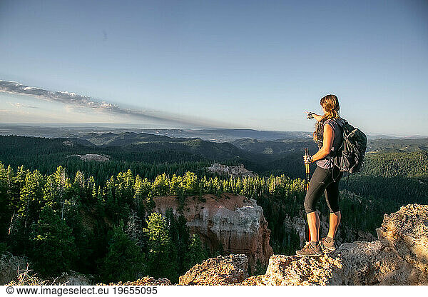 A woman in athletic clothing points to the horizon