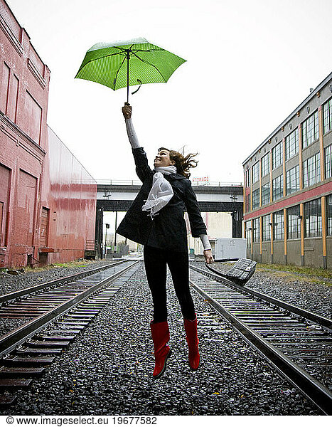 A woman in the air holding an umbrella.