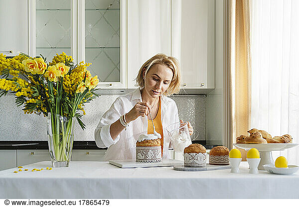 A woman in the kitchen decorates Easter pastries.