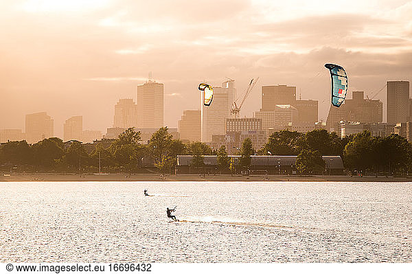 A woman kiteboarding on a summer afternoon with the Boston skyline