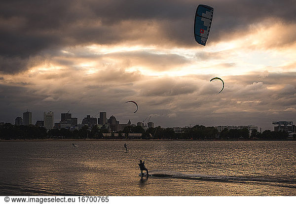 A woman kiteboarding on a summer evening with a cloudy Boston skyline