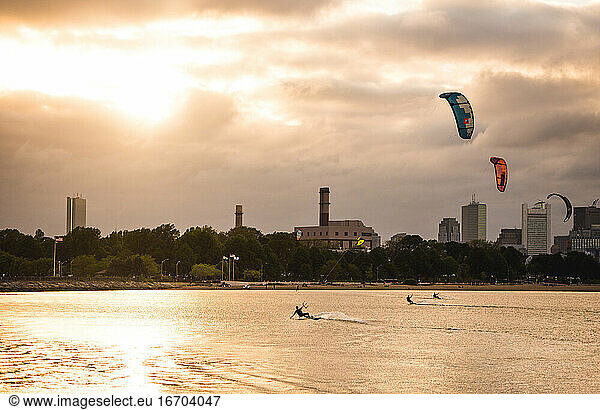A woman kiteboarding on a summer evening with a cloudy Boston skyline