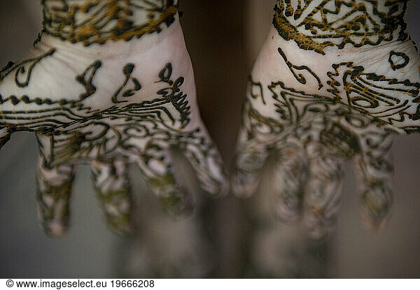 A woman lets her henna tattoo dry on her hands and feet.