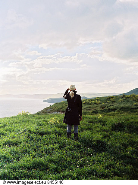 A woman looking along the coastline  inlets and cliffs.