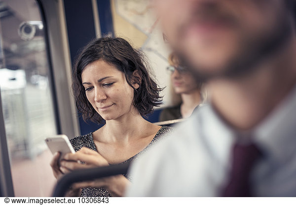 A woman on a bus looking down at her cell phone