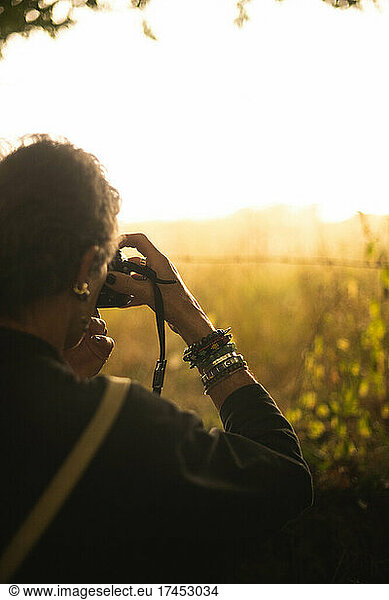 A woman photographs a sunset