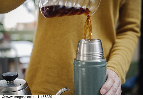 A woman pouring coffee into a flask.