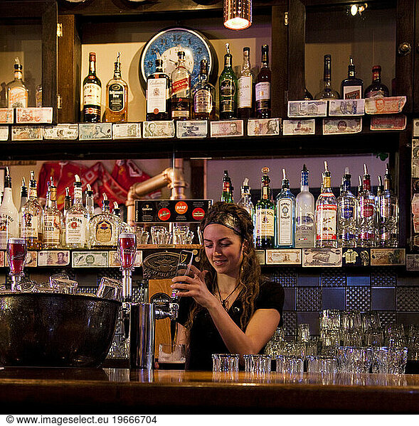 A woman pours a beer at a bar.