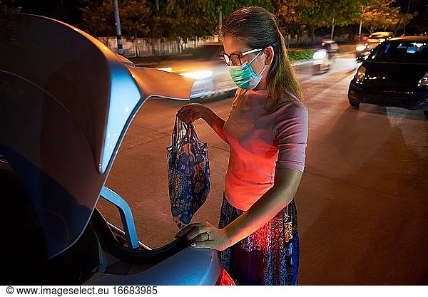 A woman put her belonging to the car trunk after shopping during COVID