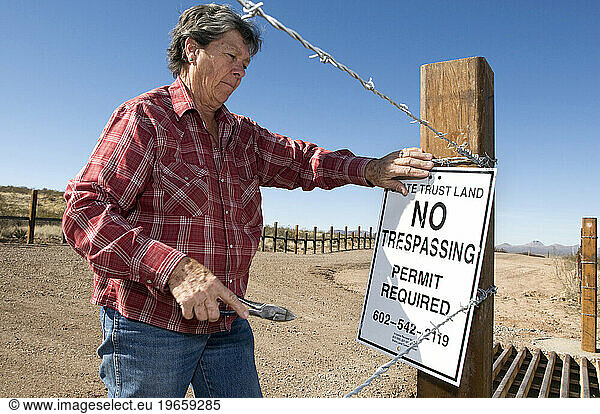 A woman puts up a No Trespassing sign on the US Mexico border in Arizona.
