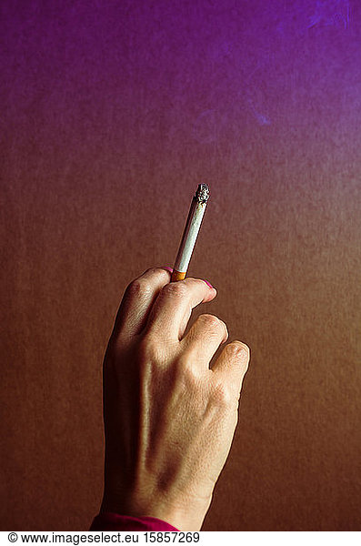 A woman's hand  with a lit cigarette.