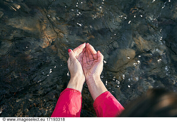 A woman's hands hold clean and natural water in the river
