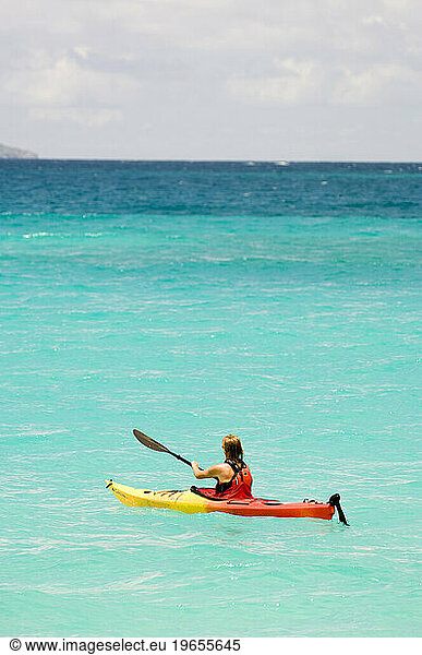 A woman sea kayaking in turqoise tropical water in Virgin Islands National Park  St. John.