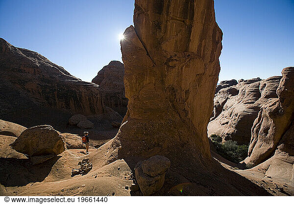 A woman standing beside rock tower  Arches National Park  Moab  Utah.