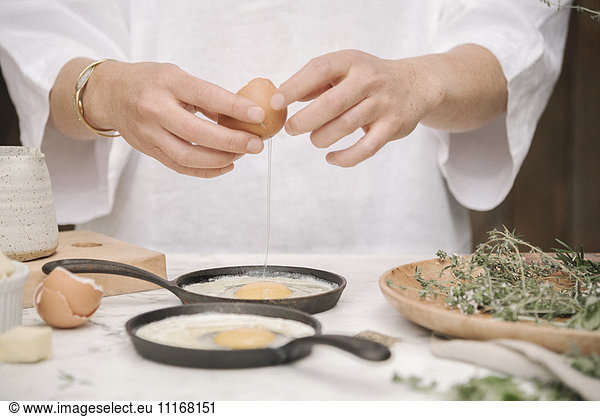 A woman standing by a table  preparing eggs for breakfast.