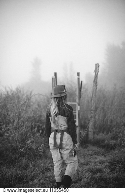 A woman standing on a wooden style in mist.