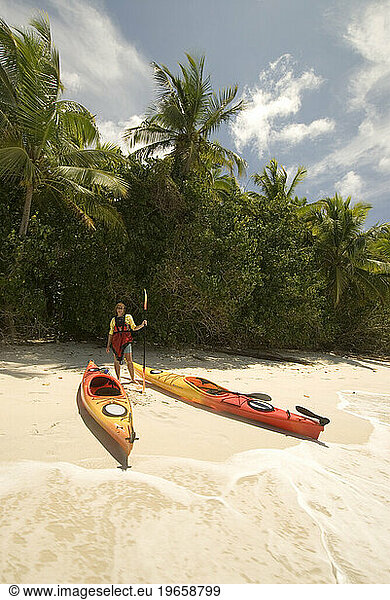A woman standing on Little Cinnamon Bay beach with her kayaks in Virgin Islands National Park  St. John.