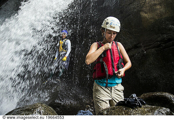 A woman stands next to a raging river and waterfall while on an adventure in Puerto Rico.