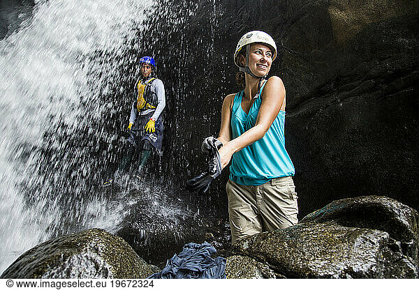 A woman stands next to a raging river and waterfall while on an adventure in Puerto Rico.