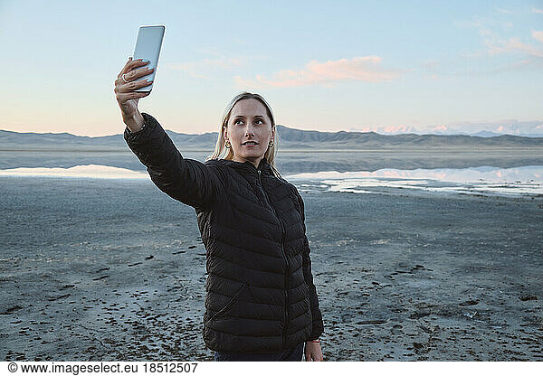 A woman takes a selfie against the background of mountains and lake
