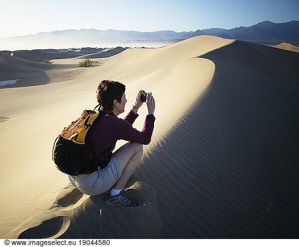 A woman taking a photograph in Death Valley National Park  California.