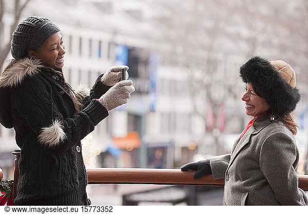 A woman taking a picture of a friend outside in wintertime with buildings in the background; Boston  Massachusetts  United States of America
