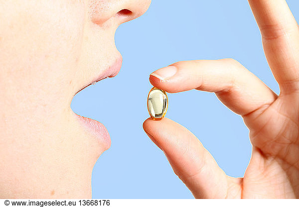 A woman taking a vitamin E supplement.
