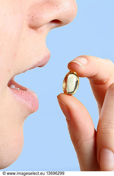 A woman taking a vitamin E supplement.