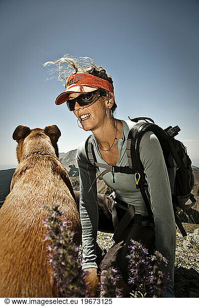A woman talks to her dog while taking a break from climbing a mountain  La Sals  Utah.