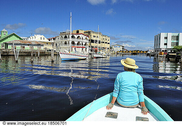 A woman tours through Belize City on the bow of a fishing boat