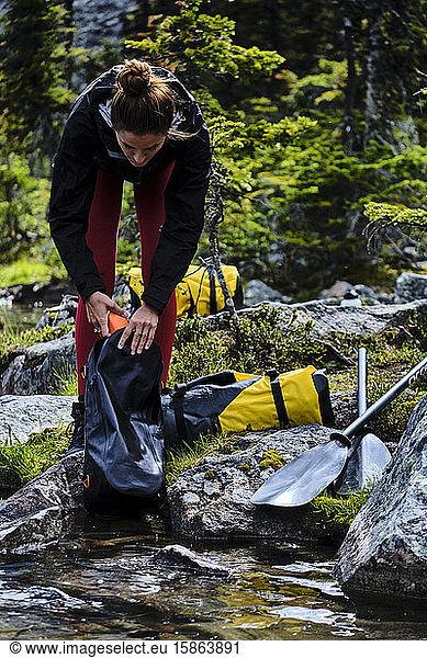 A woman unpacks her gear to prepare to packrat across Cirque Lake.