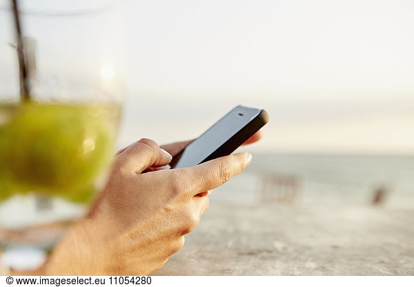 A woman using a smart phone on a beach.