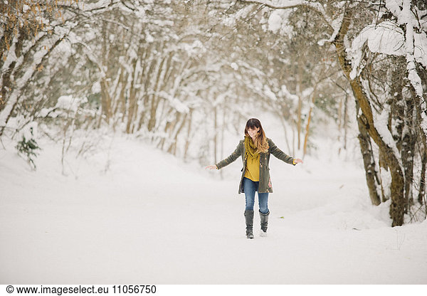 A woman walking in the snow in woodland.