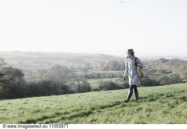 A woman walking on high ground overlooking the countryside.